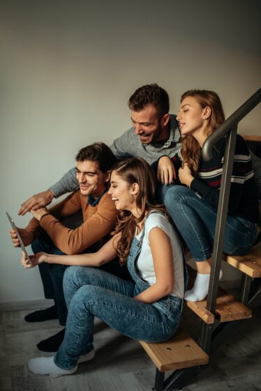imagem com várias pessoas sentadas em uma escada olhando para um tablet